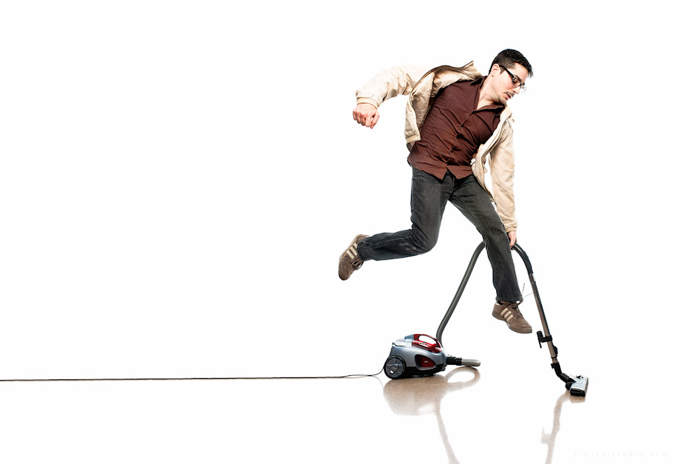 boy jumping while using a vacuum cleaner on white seamless