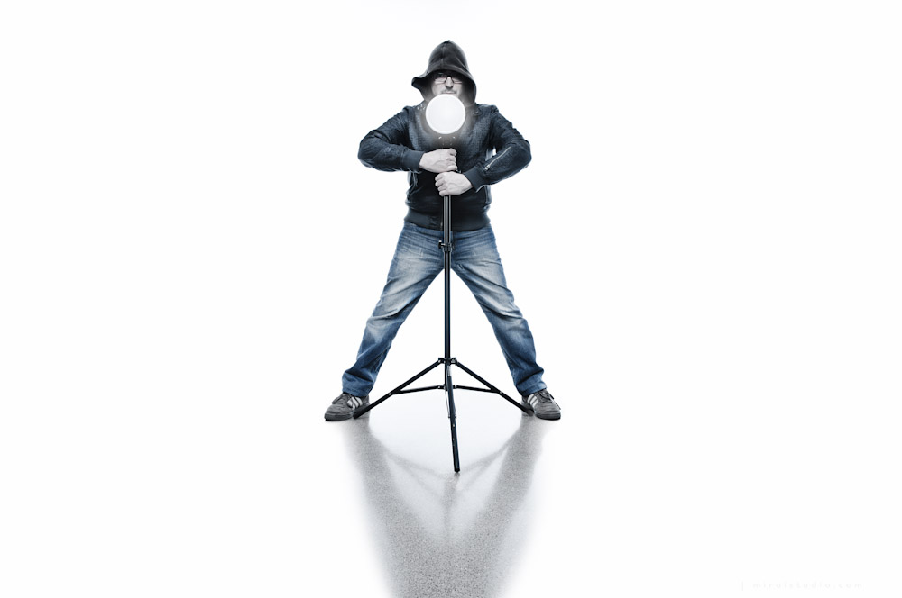 boy holding a light stand in white seamless and blueish look