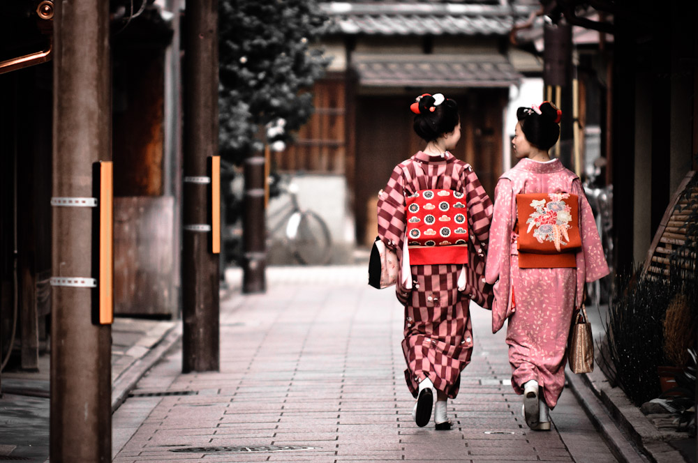 Two japanese girls walking and talking wearing kimonos