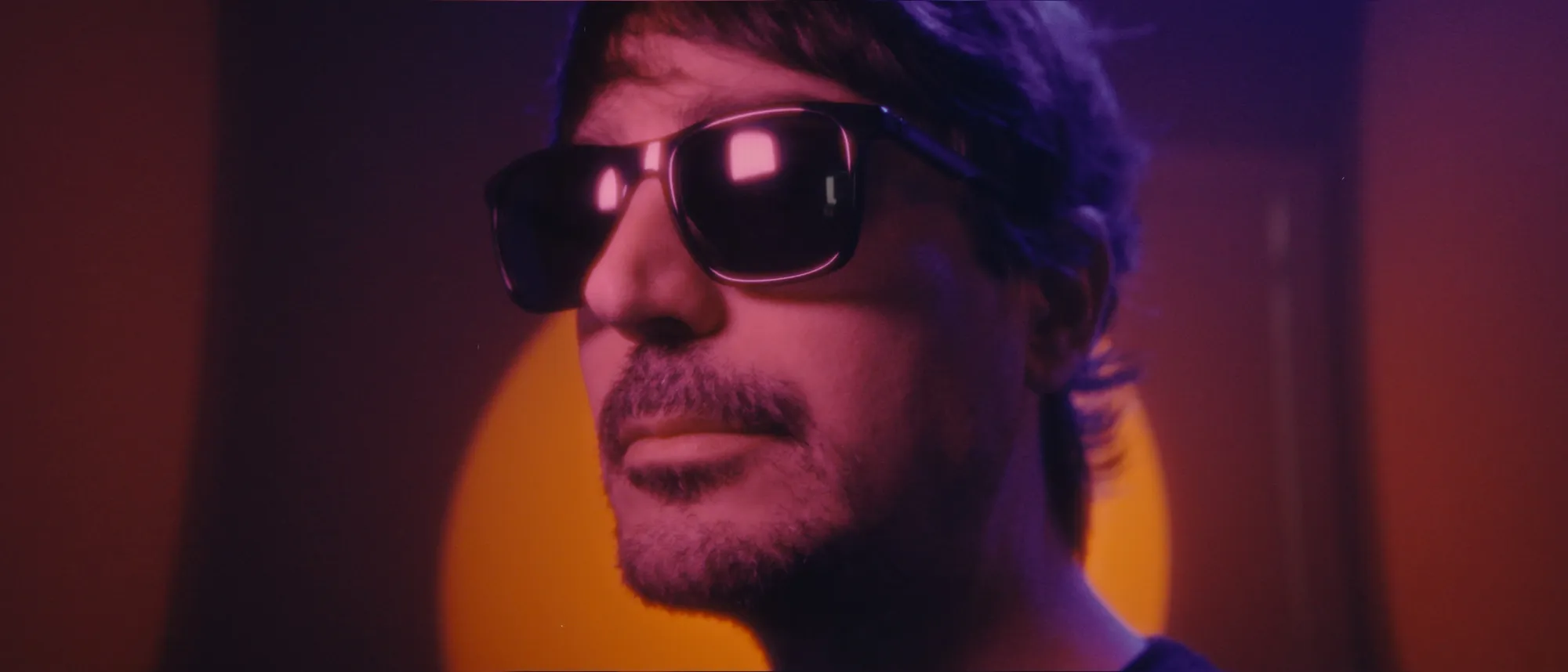 Lluís in sunglasses, lit in purple and orange