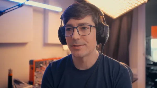 Lluís wearing headphones and glasses, talking to camera in his studio