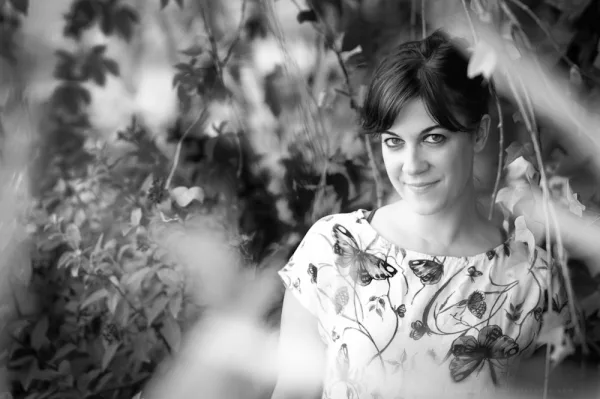 Woman among leaves and plants, in black and white