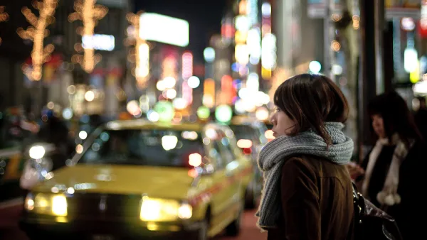 Woman in Tokyo waiting among blurry lights