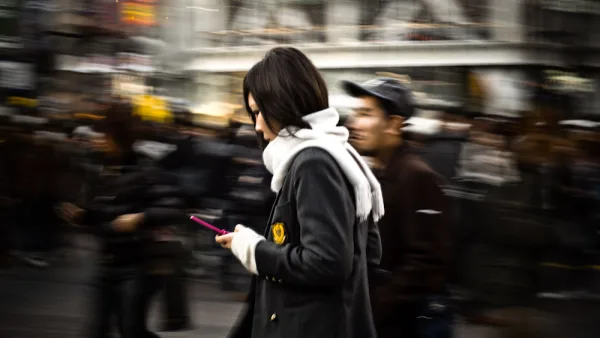 Panning shot of a woman checking her phone as she walks