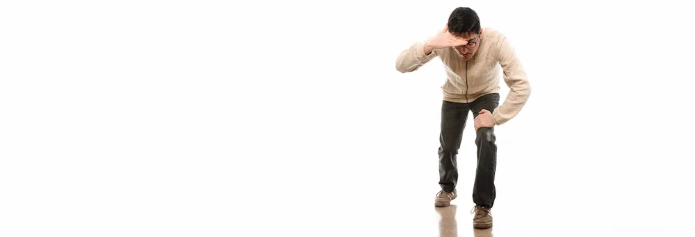 Man bending forward and looking down, on a white seamless background