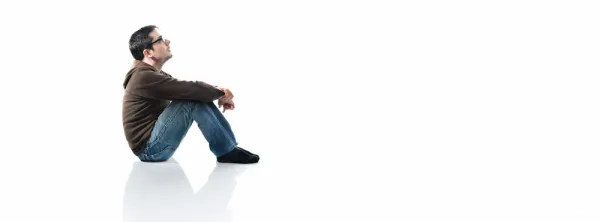 Man sitting on a white seamless background, looking up