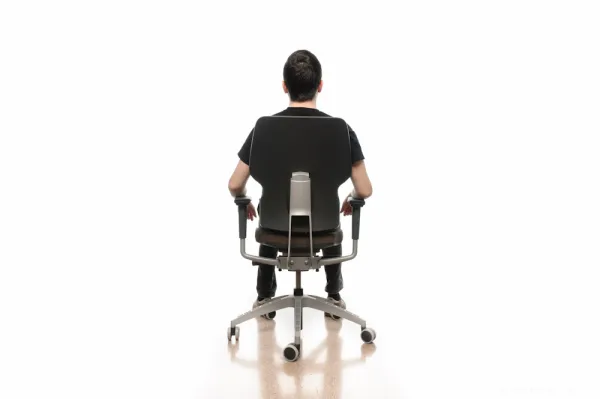 Man seen from behind, sitting on an office chair, on a white seamless background